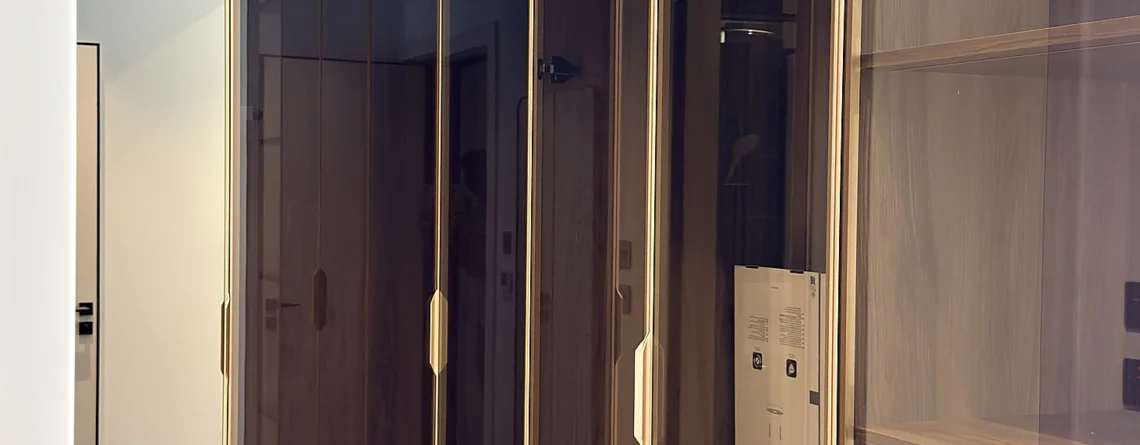 Walk-in wardrobe in Dubai with bronze glass doors and brushed brass framing
